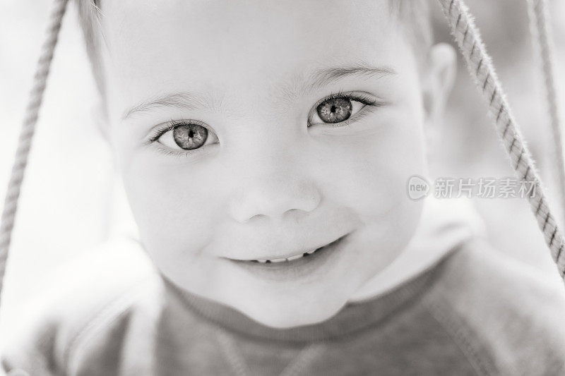 Ð¡lose-up black and white portrait of a cute boy of three years old looking with interest and smiling